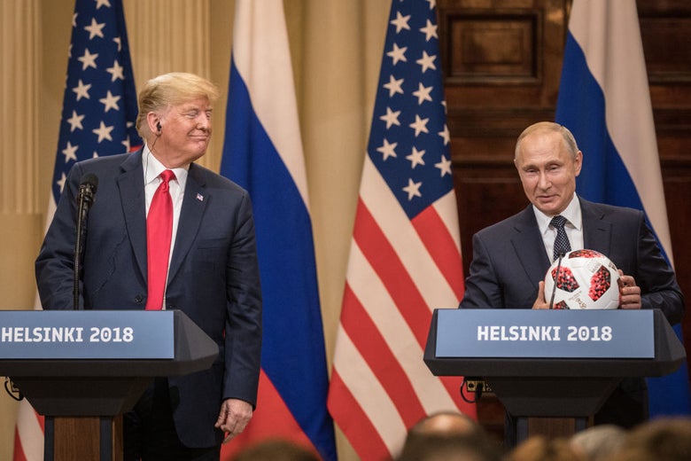 Trump smiles towards Putin, who is holding a souvenir soccer ball, as they stand at lecterns.